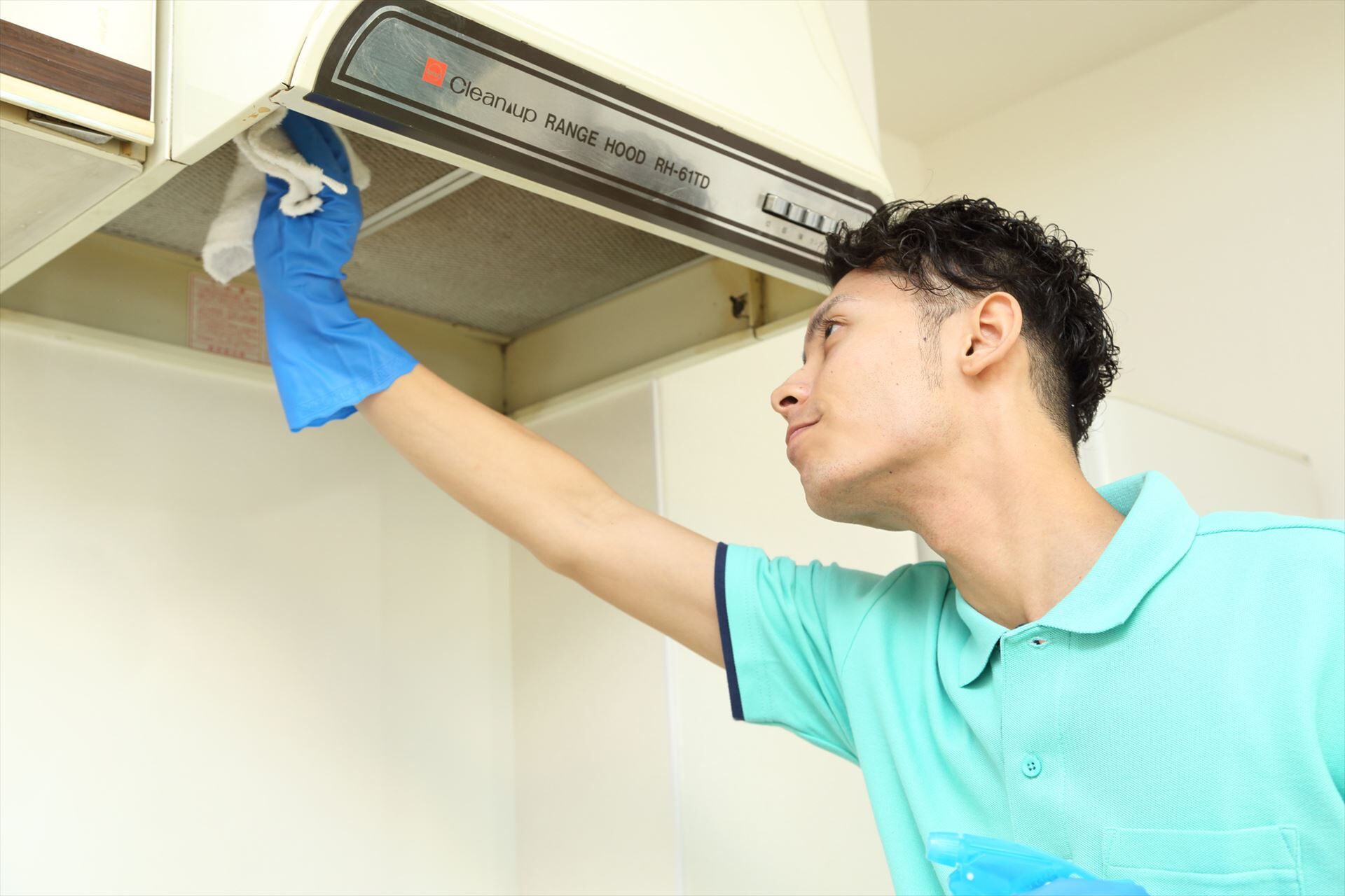 キッチンのレンジフードを掃除する男性スタッフ